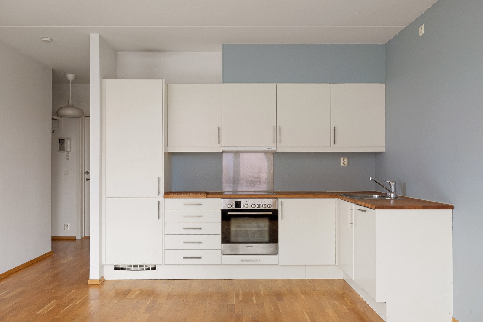 Innredet med lyse, glatte fronter, benkeplate av heltre og nedfelt oppvaskkum i rustfritt. Det er belysning under overskap. Galleribilde