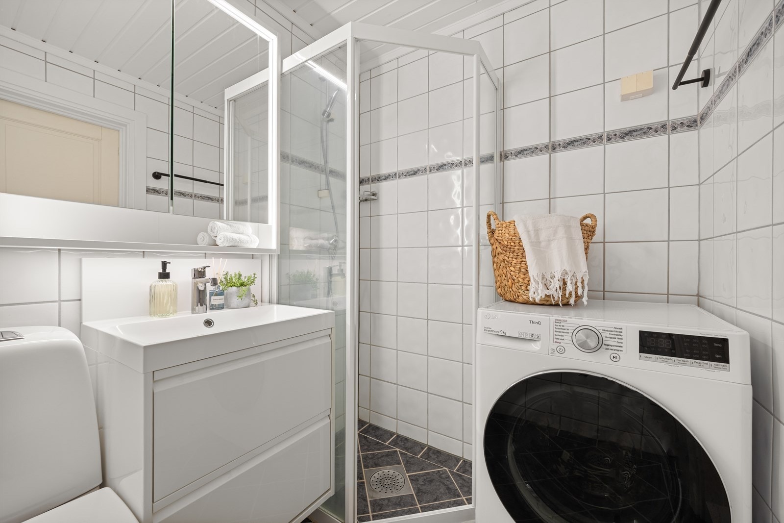 Badet er utstyrt med servantskap, vegghengt skap, frittstående toalett, dusjnisje, samt opplegg for vaskemaskin Galleribilde