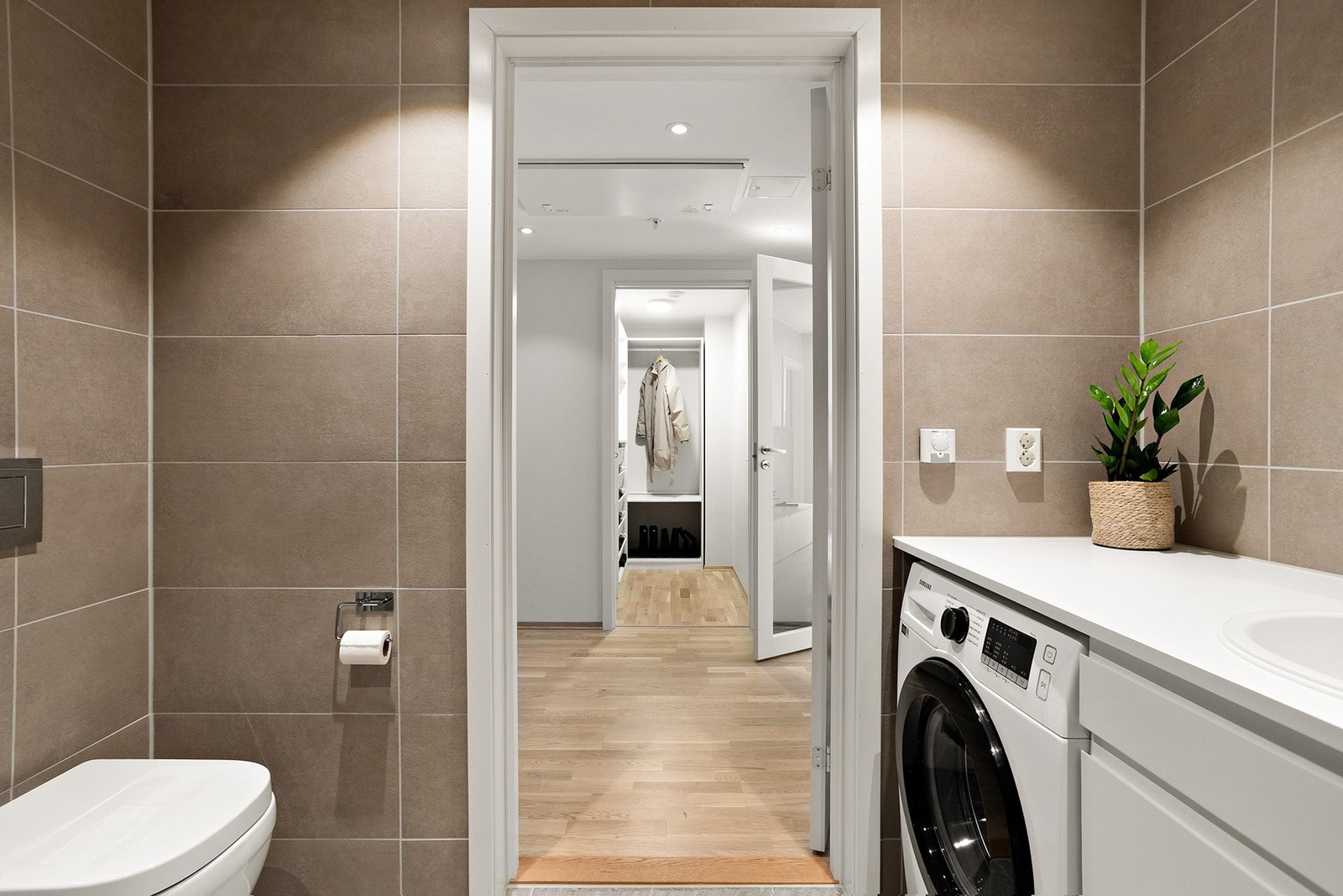 Videre er badet utstyrt med vegghengt servantskap, speil med lys, vegghengt toalett, dusjhjørne og opplegg for vaskemaskin og tørketrommel. Galleribilde