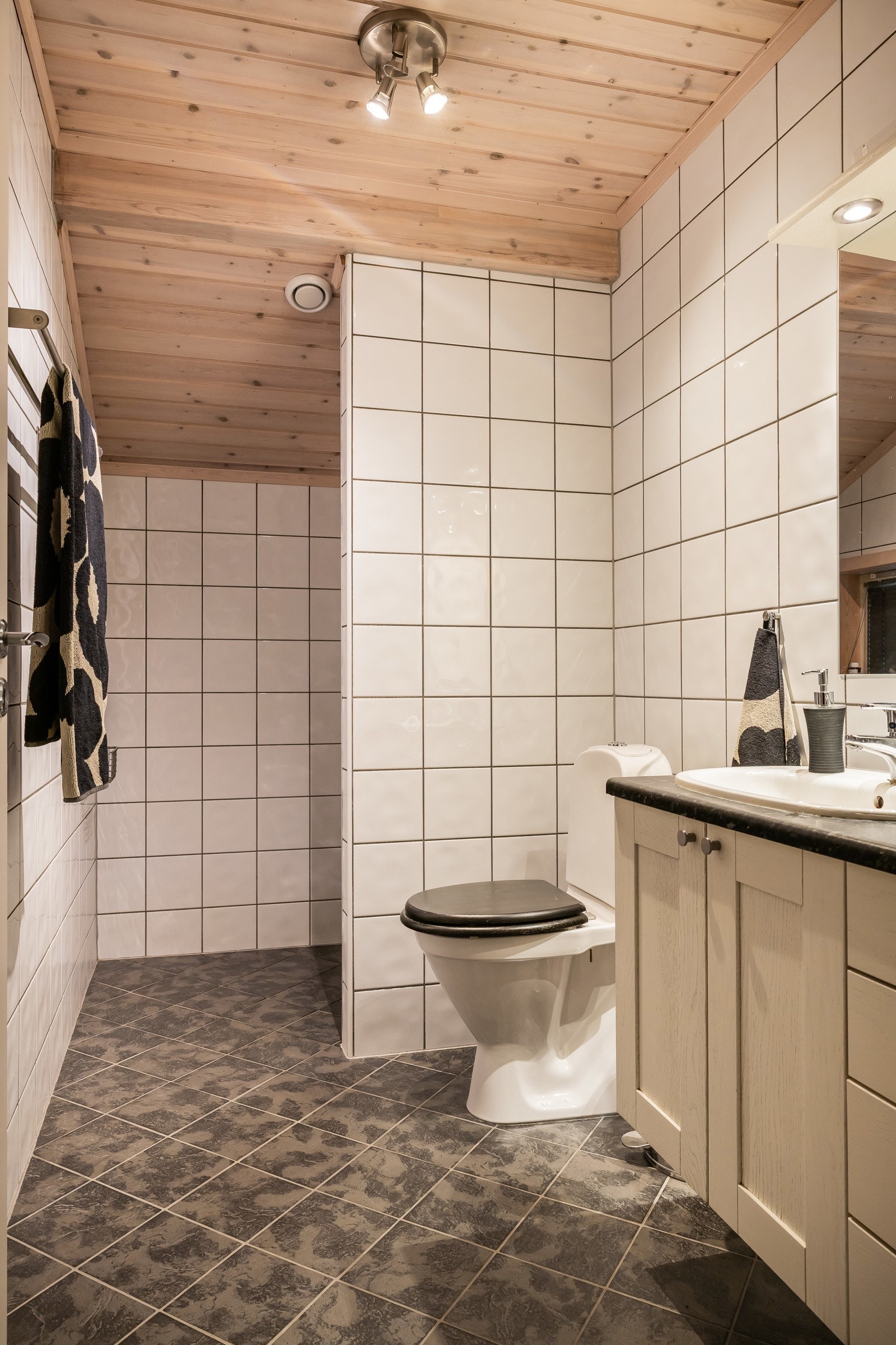 Badet i første etasje har en stilren utforming, med grå fliser på gulvet og klassiske hvite fliser på veggene. Galleribilde