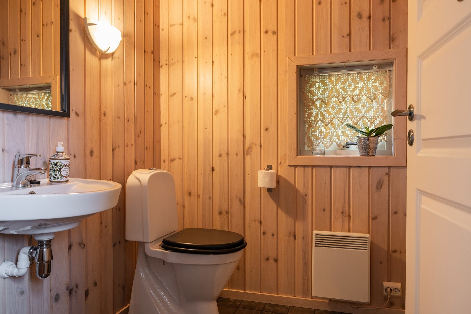 Toalettet har flislagt gulv og vegger og tak kledd med trepanel, som gir en varm og hyggelig atmosfære. Galleribilde