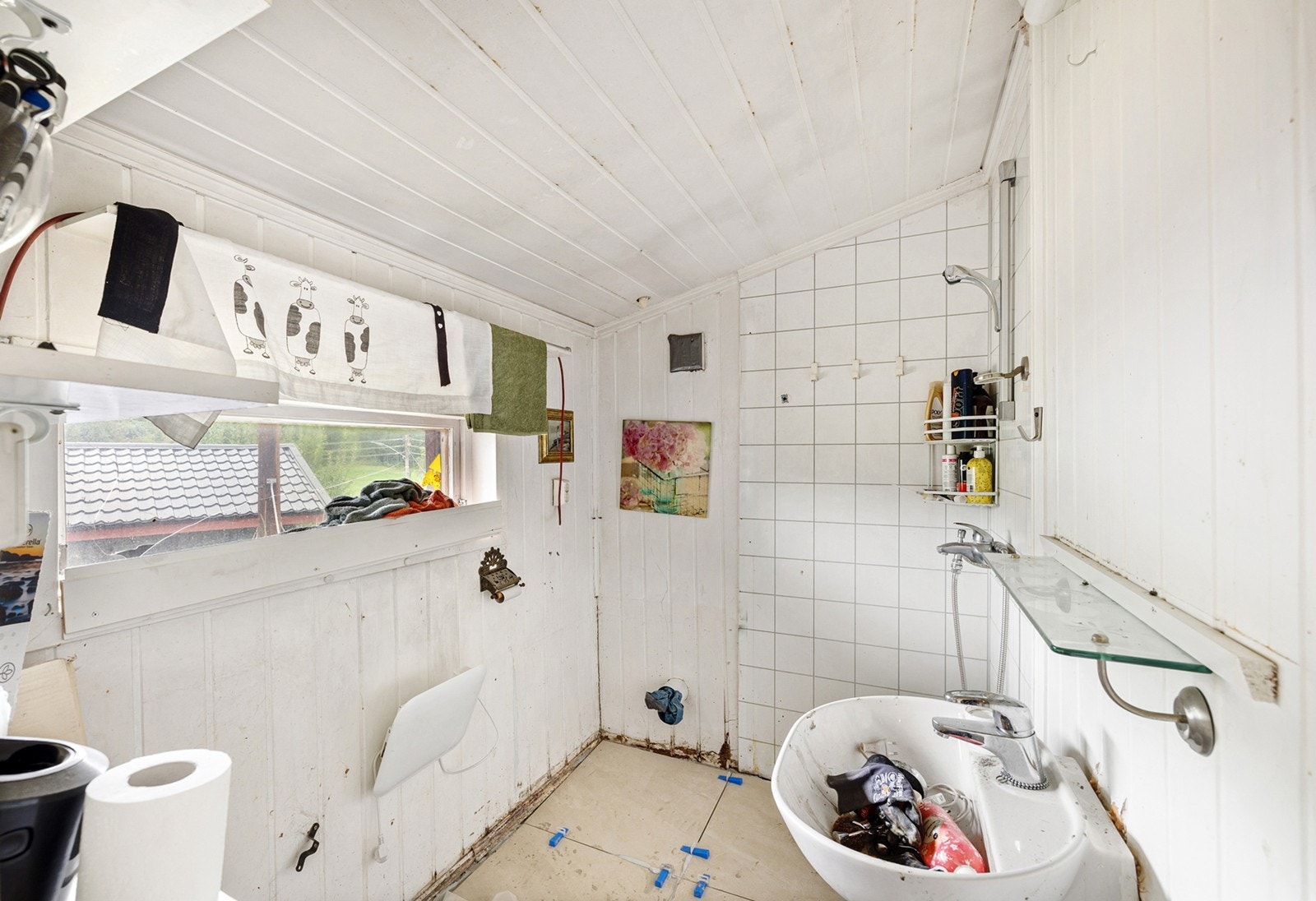 Enkelt baderom med oppgraderingsbehov. Rommet er utstyrt med dusj, servant og toalettløsning, samt et vindu som slipper inn naturlig lys og gir mulighet for lufting. Galleribilde