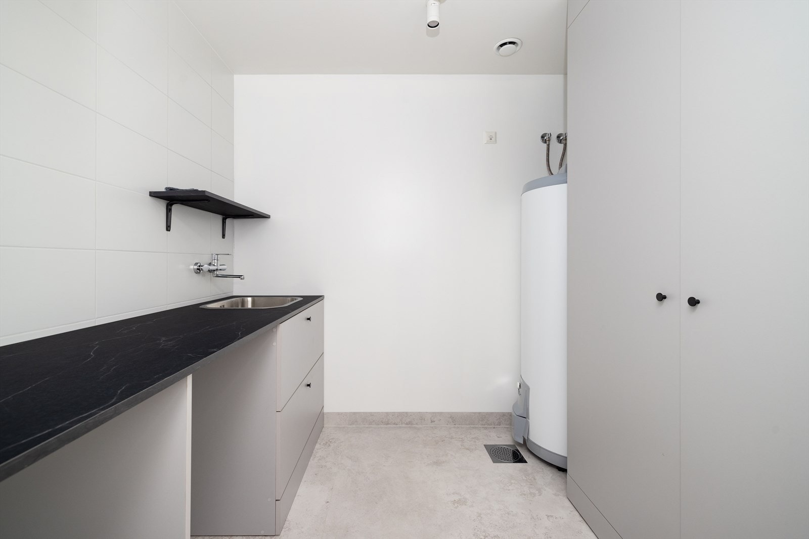 Inntil badet ligger vaskerommet, som også er nytt i 2023. Vaskerommet er på 5,5 m2 og har fliser på gulv med varmekabler. Her er en praktisk arbeidsbenk med nedfelt stålvask, med opplegg og plass til vaskemaskin og tørketrommel under benk. Galleribilde