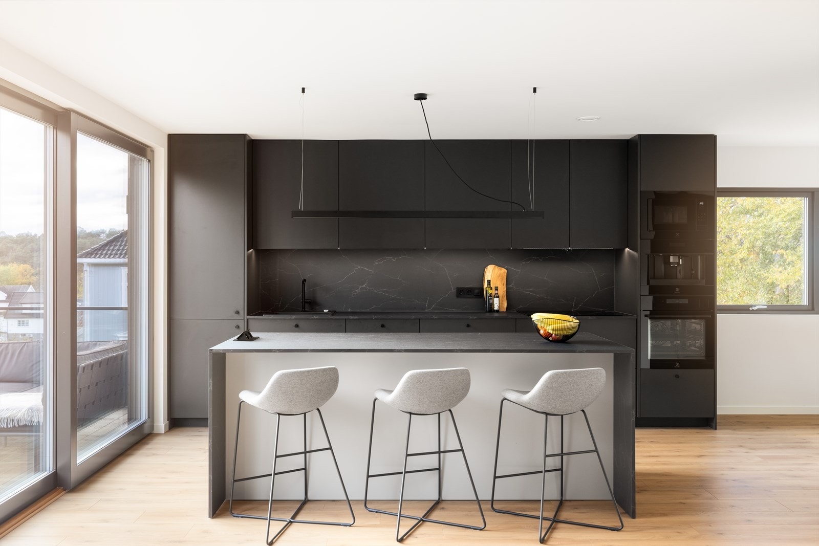 Som et naturlig skille mot dagligstuen er det etablert en kjøkkenøy med barløsning og sitteplasser på den ene siden, og oppbevaringsplass på den andre siden. Galleribilde