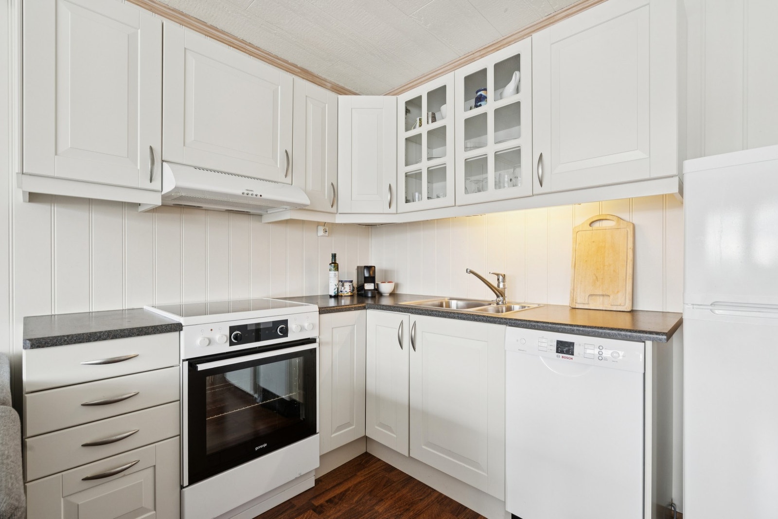 Leiligheten har et tidløst og funksjonelt kjøkken- Benkeplate i laminat, og hvite profilerte fronter Galleribilde