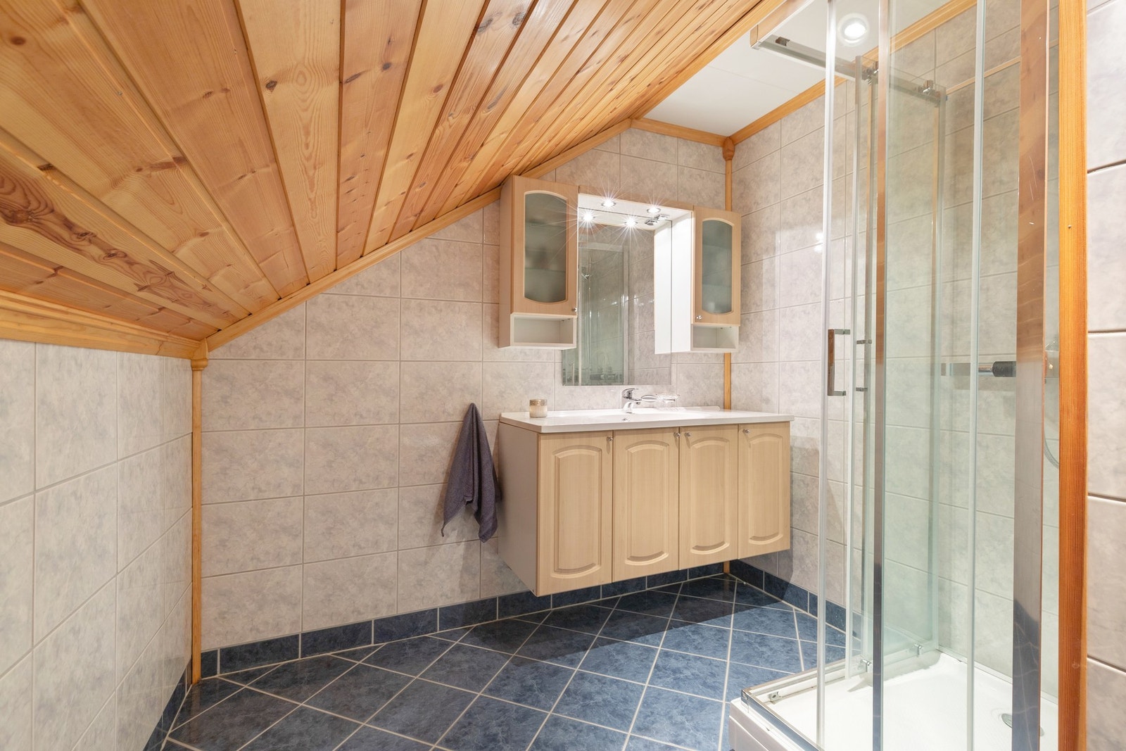 Flislagt baderom på loft med innredning med nedfelt servant. Galleribilde