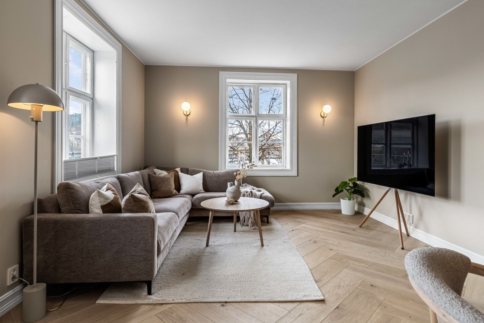 Innbydende stue med fiskebensparkett i eik og malt gips på vegger og i tak. Galleribilde
