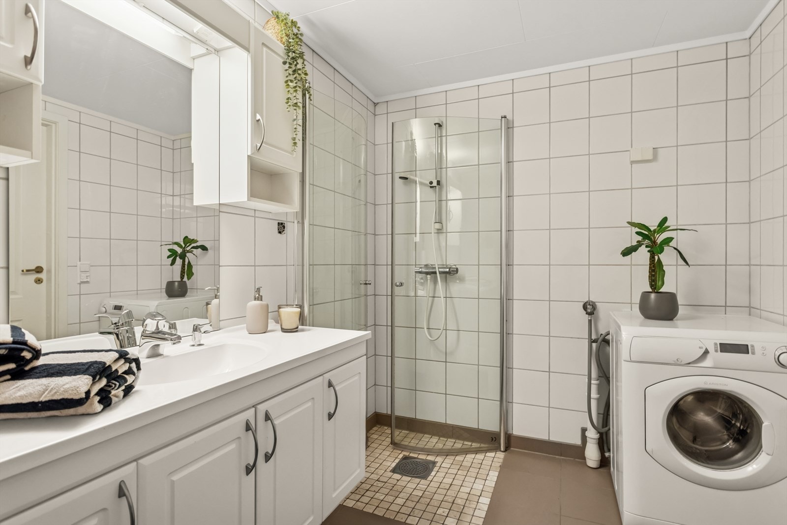 Rommet har dusjdører i glass, dusjgarnityr på vegg, innredning med servant, toalett og opplegg til vaskemaskin. Et godt sted å starte dagen! Galleribilde