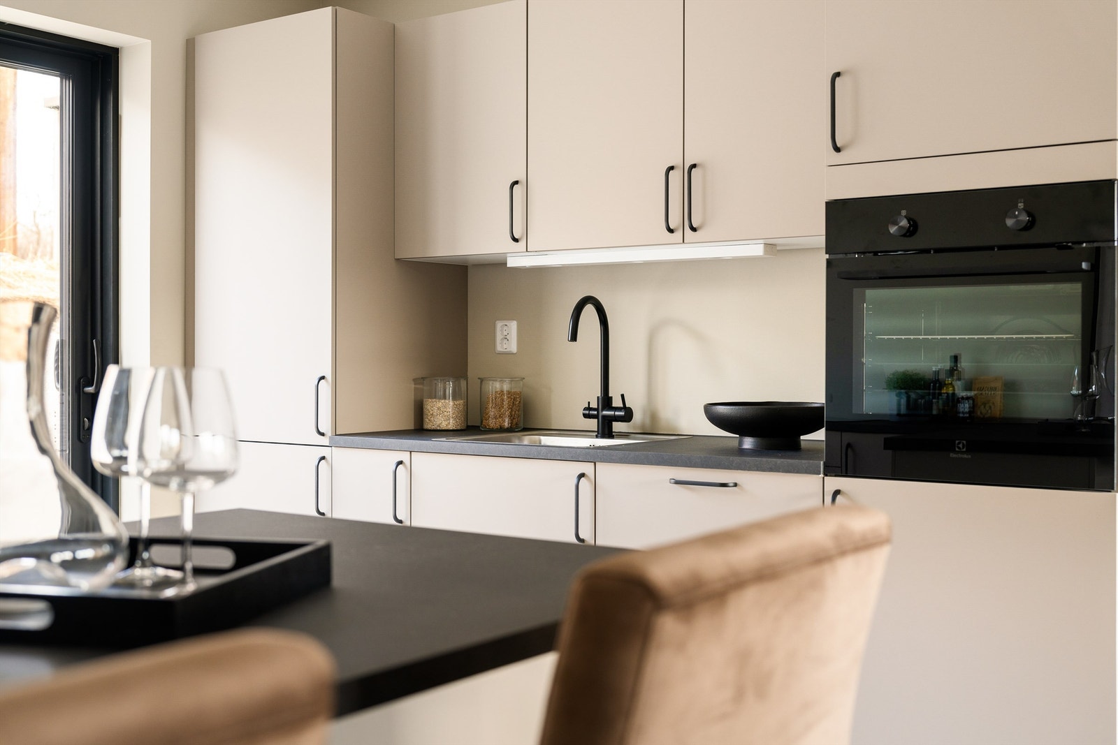 Det moderne kjøkkenet har lyse fronter og mørke benkeplater. Galleribilde