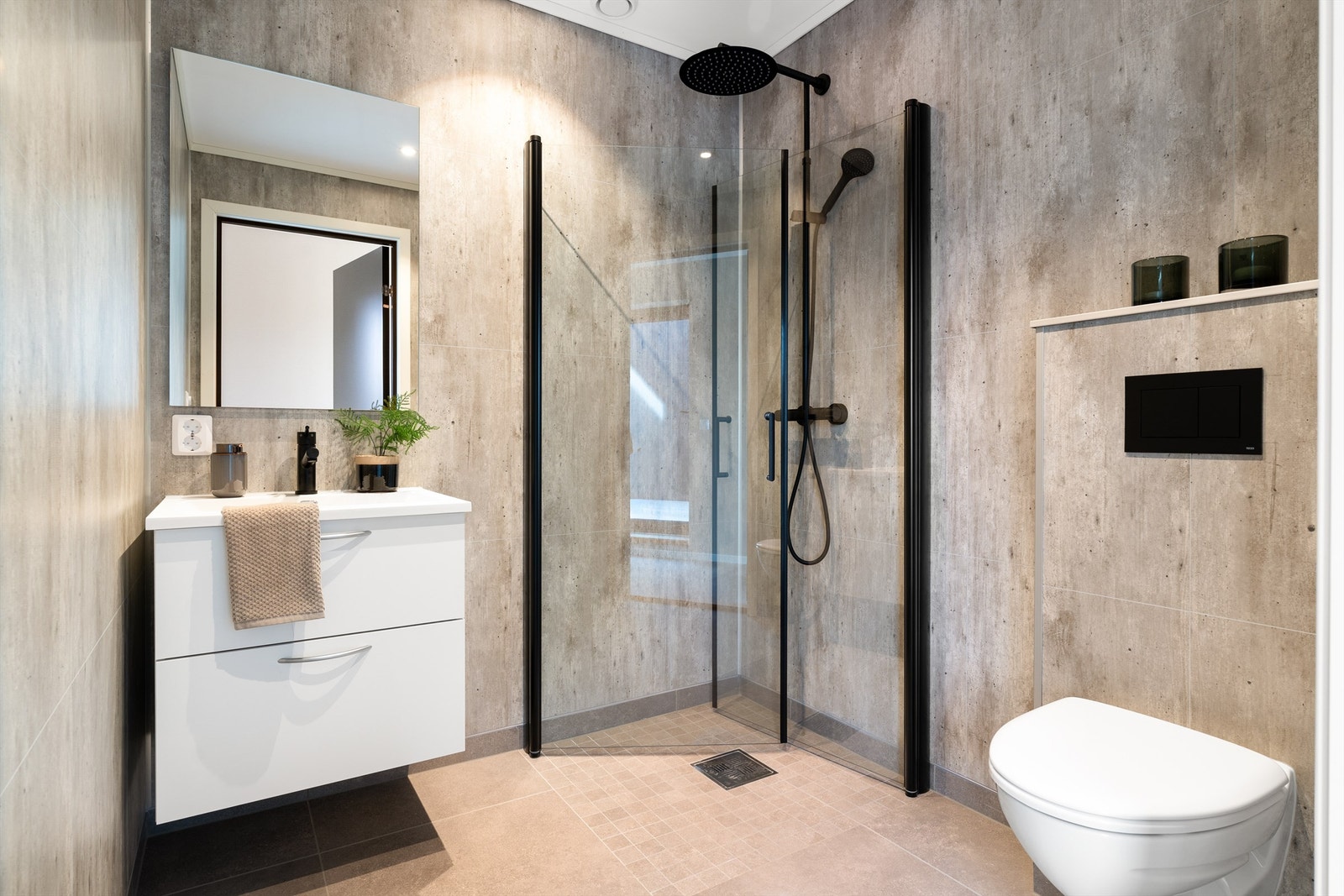 Badet i loftetasjen har moderne grå fliser, en dusjkrok med glassvegger, et vegghengt toalett og en servant med oppbevaringsmuligheter. Galleribilde