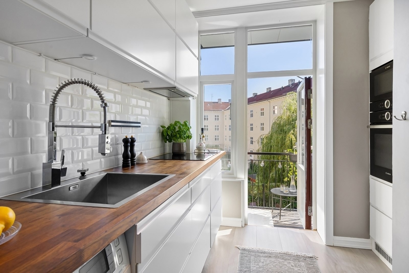 Kjøkkenet har slette, lyse fronter, fliser på vegg, belysning under overskap og heltre benkeplate. Galleribilde