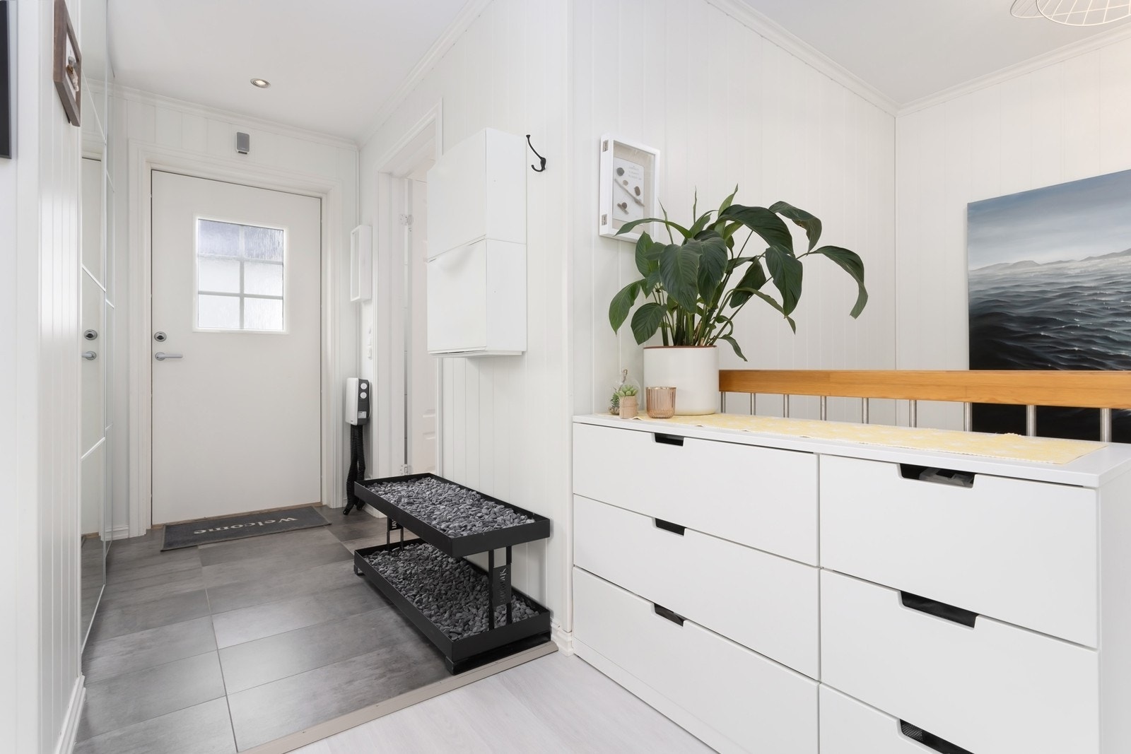 Boligen har en flislagt entre med god plass til oppbevaring i skyvedørsgarderobe med speil. Galleribilde
