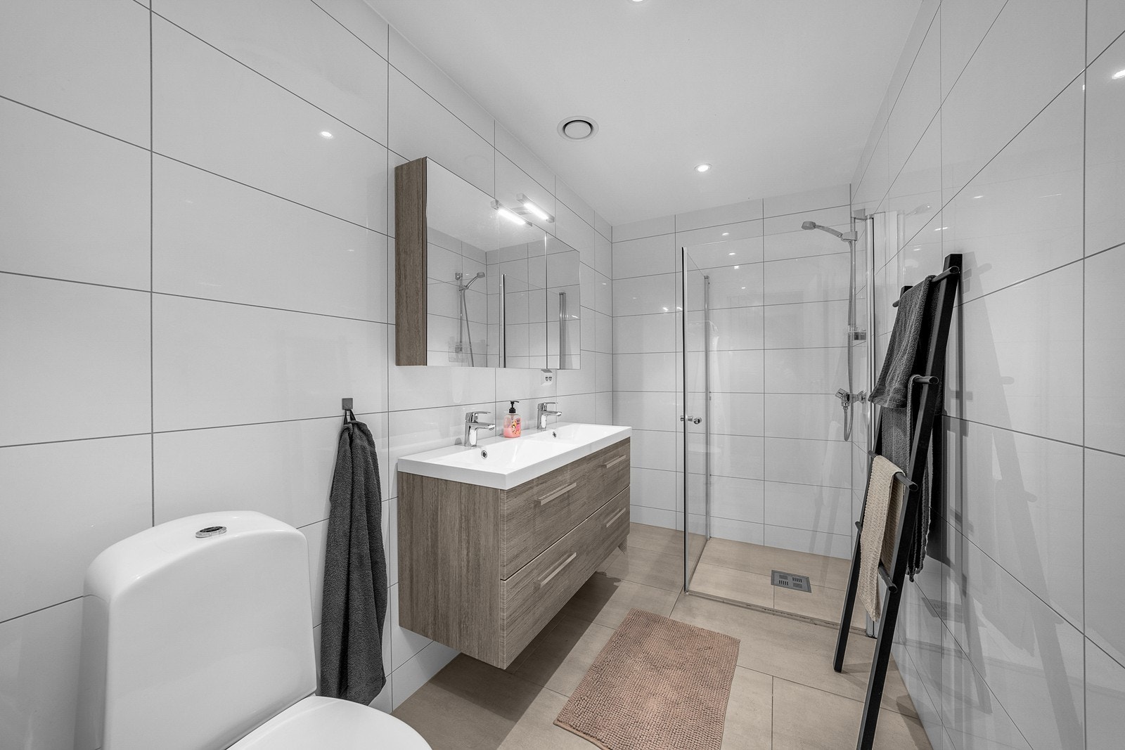 Flislagt bad i første etasje. Badet har downlights, gulvvarme, dusjhjørne med innfellbare dusjvegger, heldekkende servant med skuffer og frittstående toalett. Galleribilde