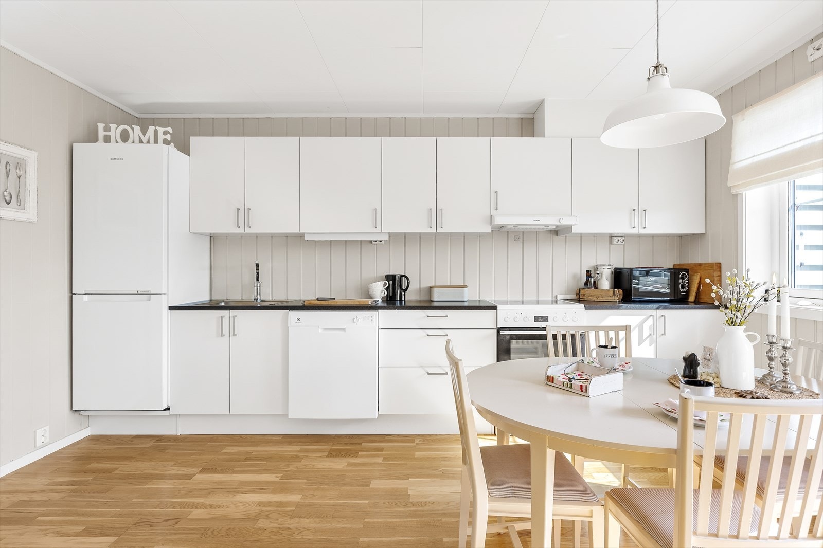 Innredningen har hvite, glatte fronter og koksgrå laminatbenkeplate med nedfelt kum i stål. Galleribilde