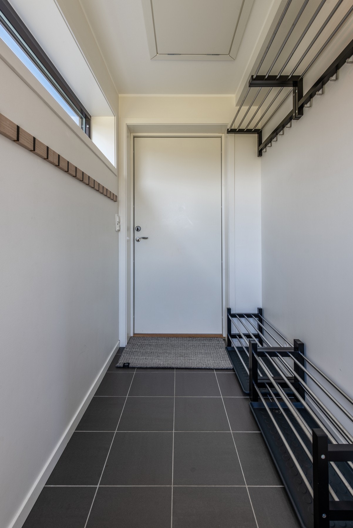 Flislagt entré med lang knaggrekke og god plass til oppbevaring av yttertøy Galleribilde