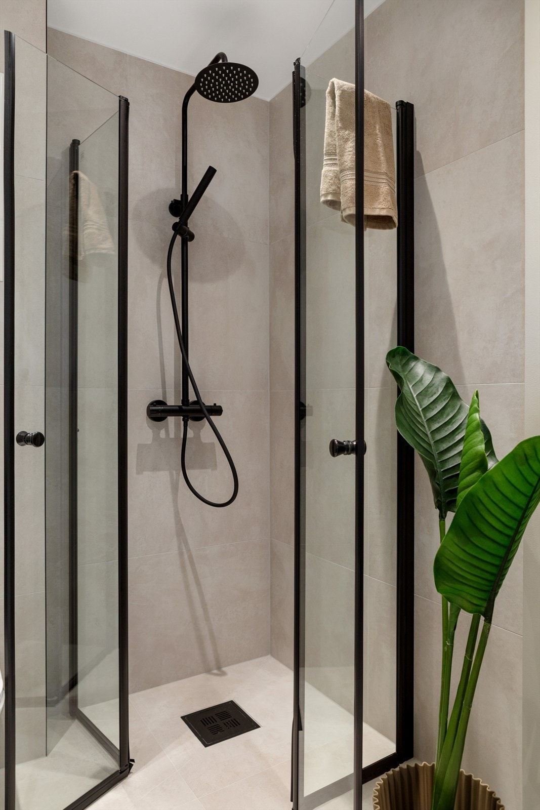 Dusjhjørne med glassvegger, veggmontert toalett, samt opplegg for vaskemaskin. Et baderom som kombinerer funksjonalitet med et elegant uttrykk. Galleribilde