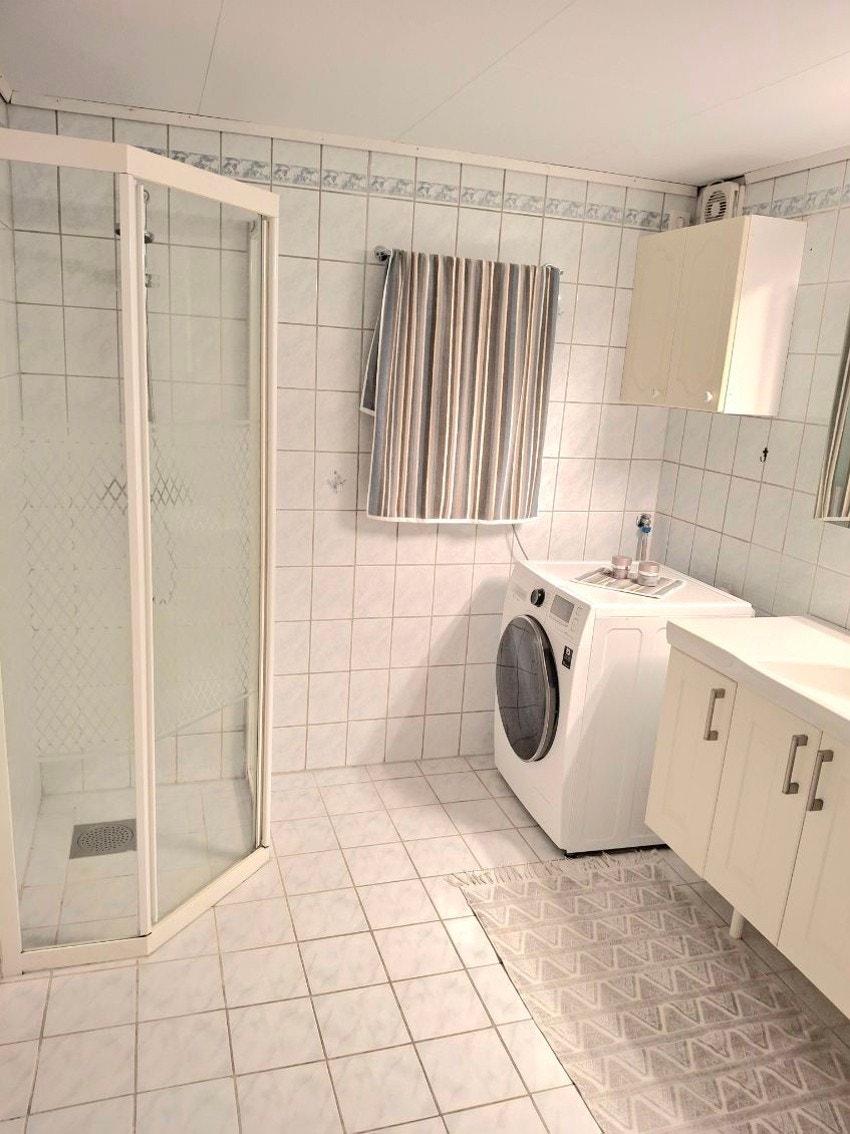 Flislagt baderom med opplegg for vaskemaskin og god plass til oppbevaring. Galleribilde