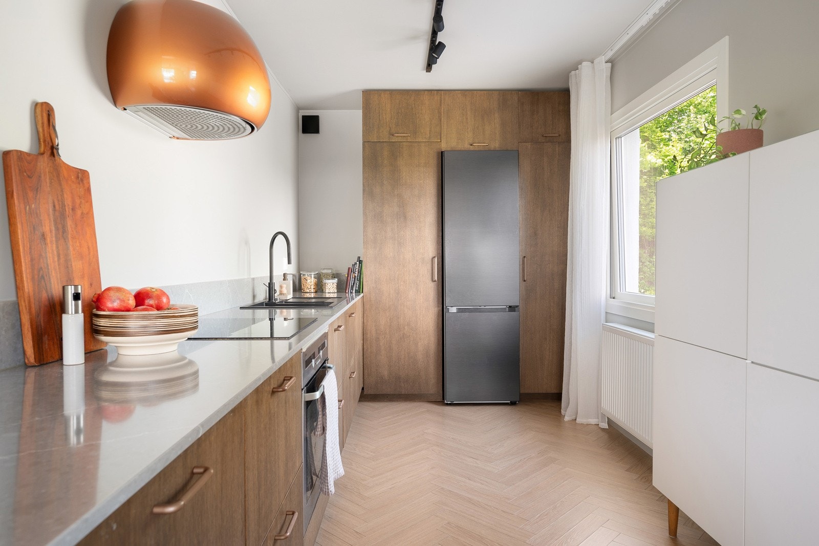 Kjøkkeninnredning med tilpassede fronter, benkeplate av komposittstein og godt med oppbevaringsplass. Galleribilde