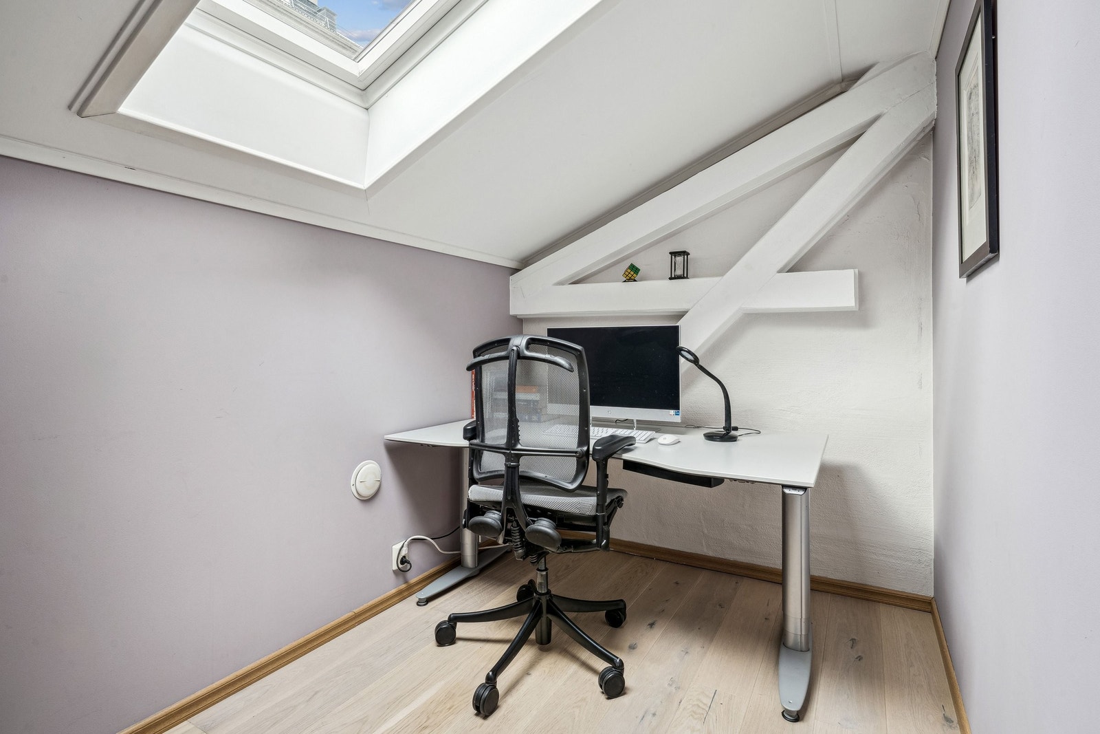 Lyst og fint soverom/kontor med nytt parkettgulv i 2021, delikat lilla farge på veggene og stort takvindu. Synlige bjelker i tak og vegger går igjen på begge soverom. Galleribilde