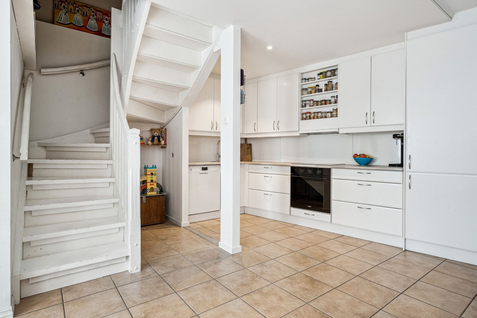 Kjøkken med flislagt gulv, gulvvarme, downlights i himling og integrerte hvitevarer. Under trappa har nåværende eier en liten lesekrok for barna. Galleribilde
