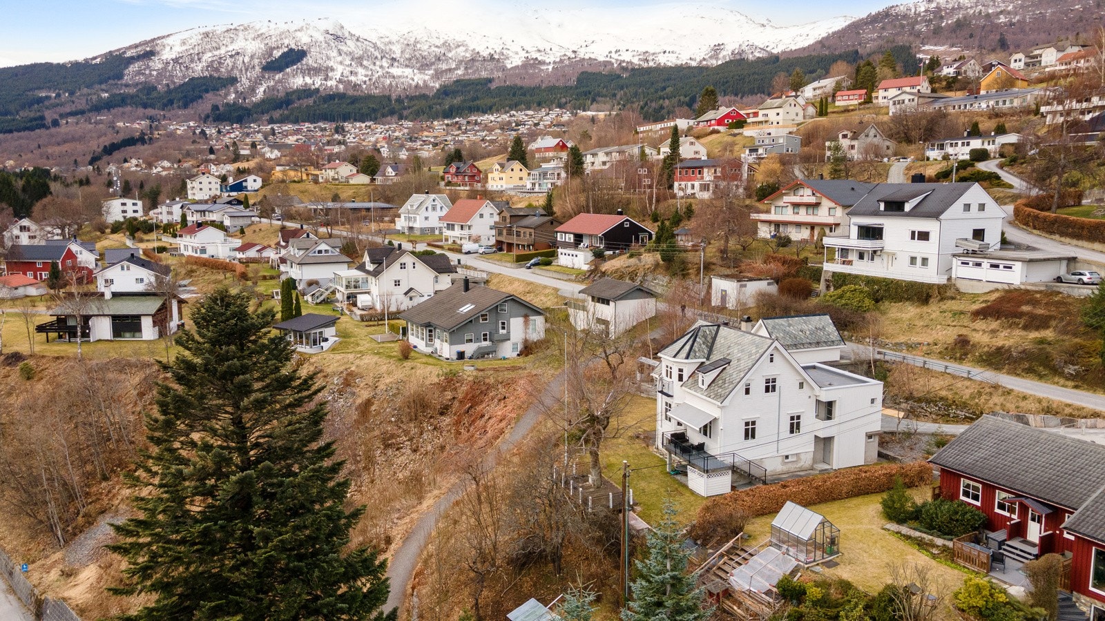 Tomten er pent opparbeidet med plen, beplantning, asfaltert innkjørsel og natursteinsmurer. Galleribilde