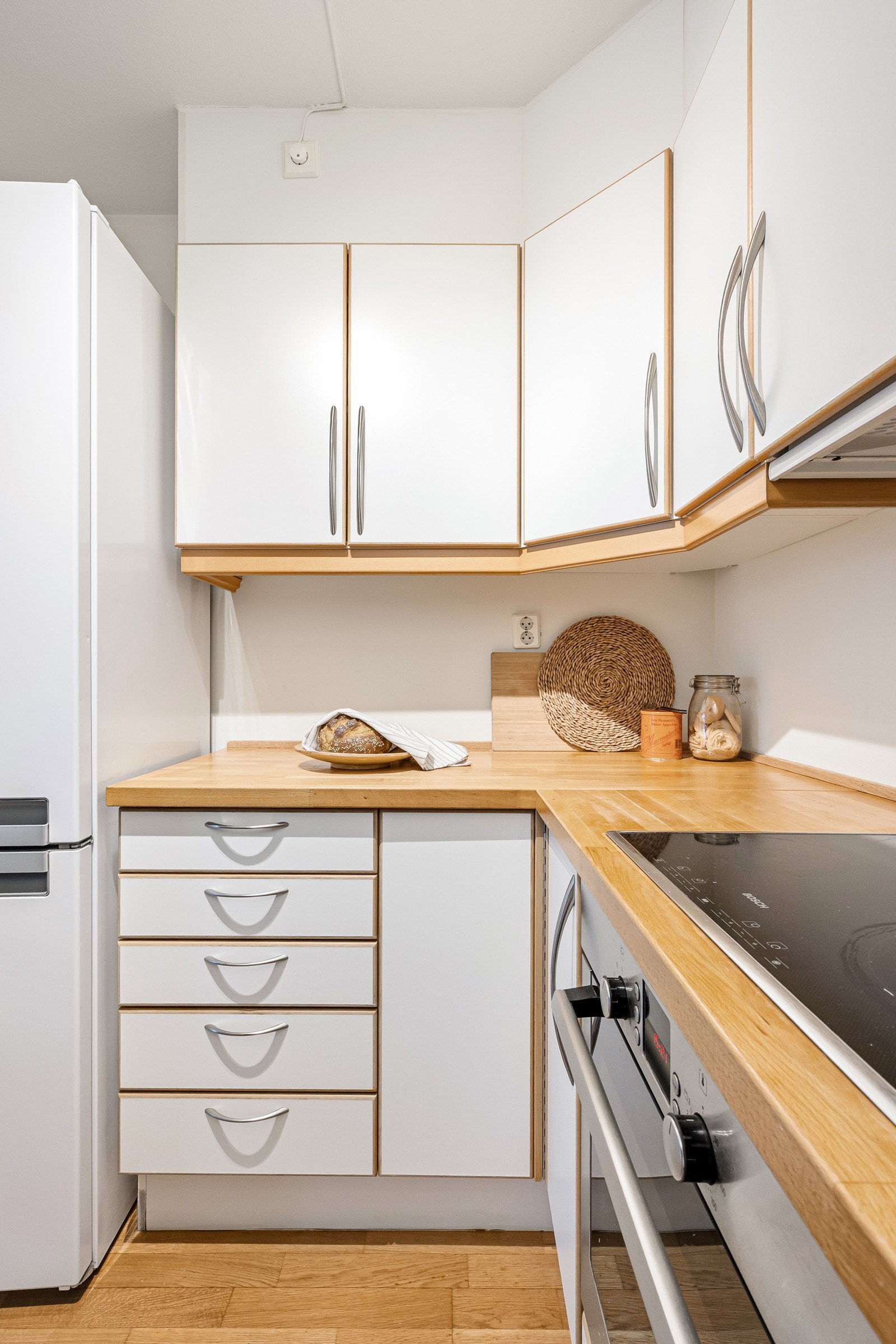 Kjøkkenet har glatte, hvite fronter med trehvit ramme og benkeplater i limtre med nedfelt vaskekum i stål. Galleribilde