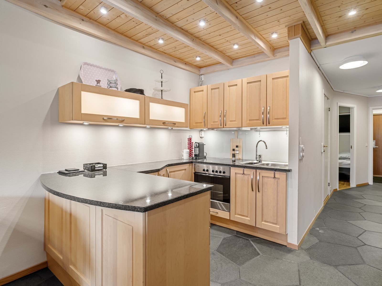 Benkeplate i stein og god belysning over kjøkkenbenk. Integrert komfyr. Galleribilde