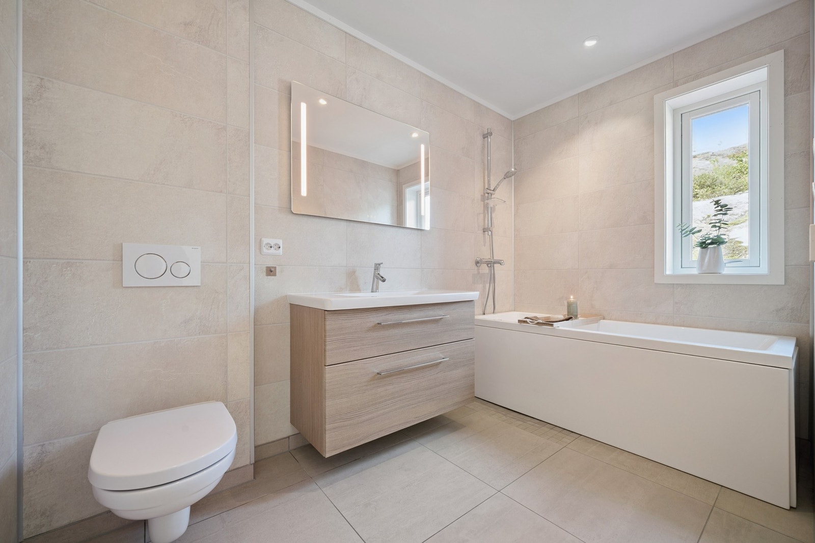 Lekkert bad i 2. etasje - flislagt og moderne med vegghengt toalett, stilren baderomsinnredning og badekar med dusjløsning Galleribilde