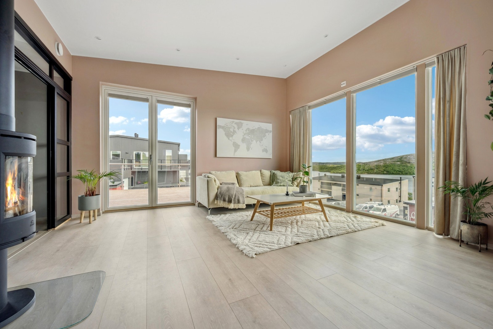 Lun stue malt i rolige jordfarger - store vindusflater helt ned til gulv og dobbel terrassedør gir flott lysinnslipp og utgang til stor terrasse Galleribilde