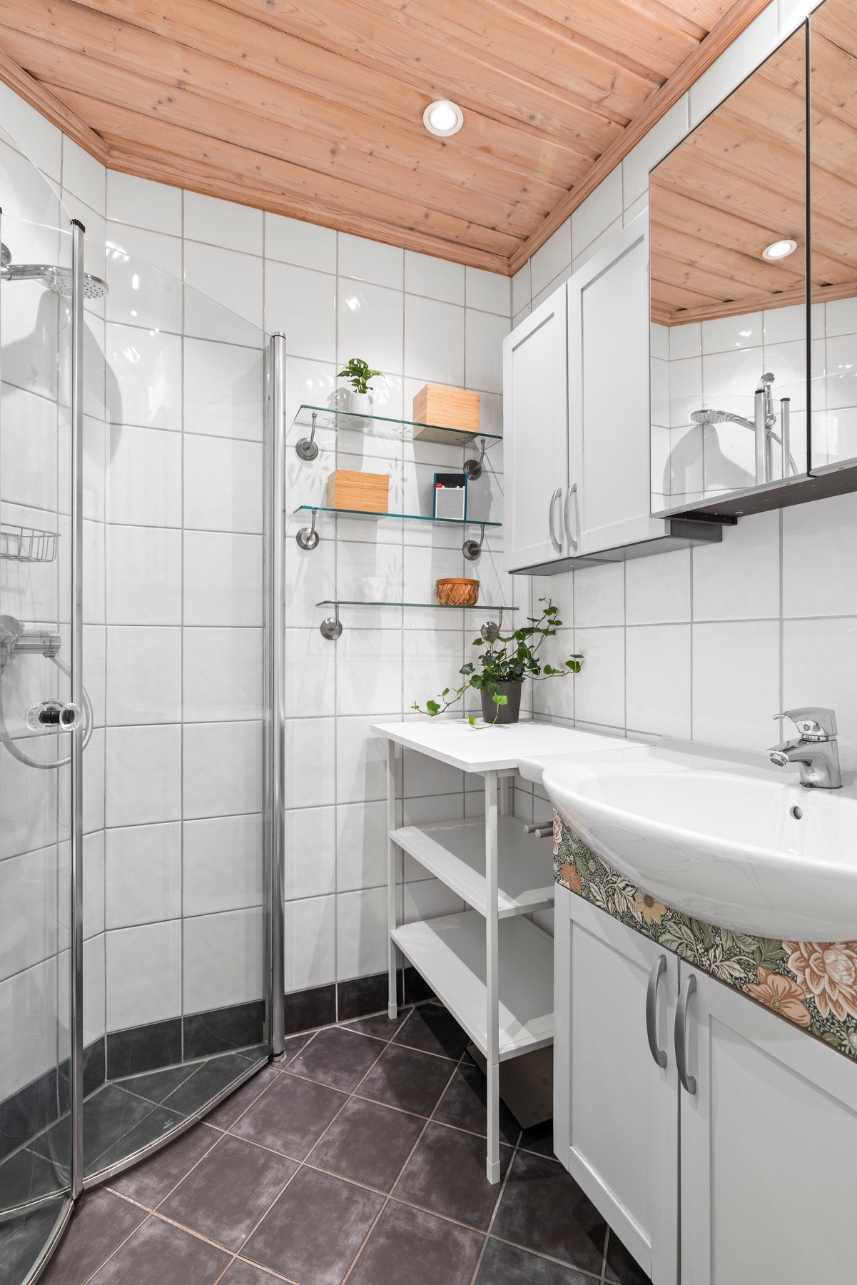 Innredning med dusjhjørne med glassdører, vegghengt servantskap med speilskap, toalett og gulvvarme som gir en lun og behagelig opplevelse. Galleribilde