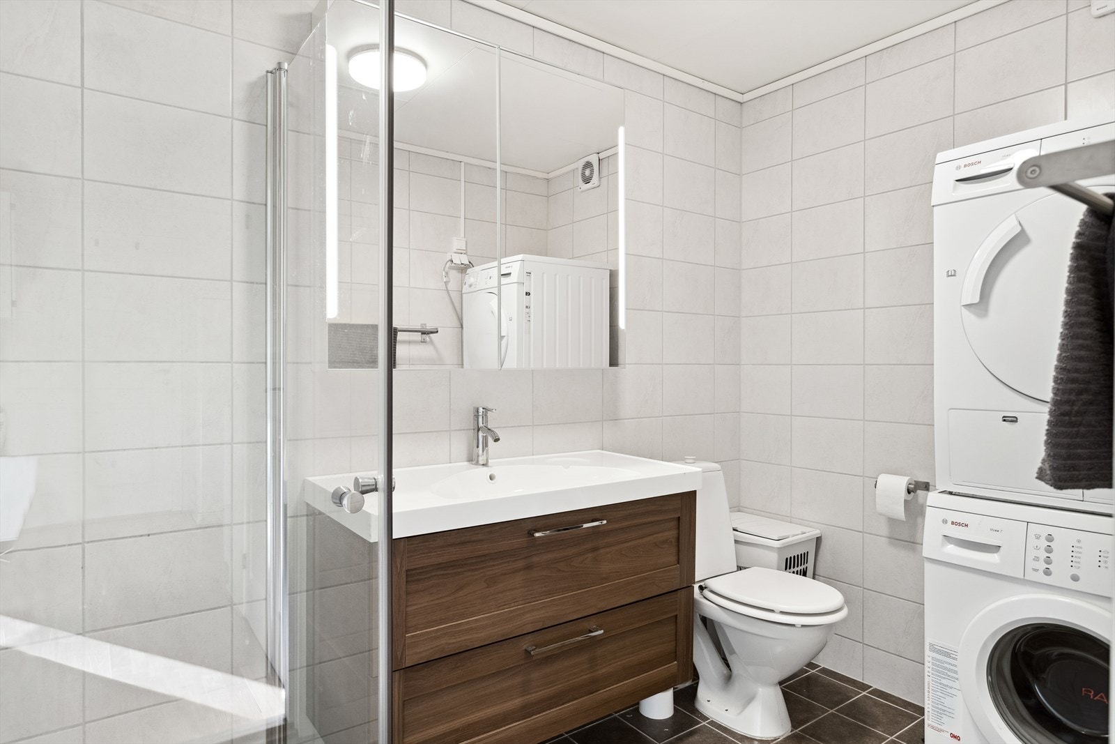 Baderommet i utleiedelen er ca 4,9 m² og har flis på gulv og vegg, takplater i himling. Oppgradert i 2014. Dusjvegger av glass, gulvmontert toalett, innredning med servant samt opplegg for vaskemaskin Galleribilde