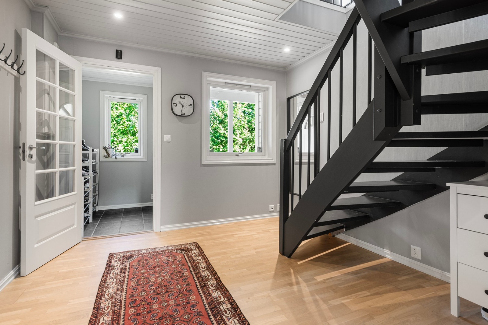 Fra flislagt entré kommer du inn i lys og åpen trappegang med malt panel og downlights i taket som gir et godt førsteinntrykk av boligen Galleribilde