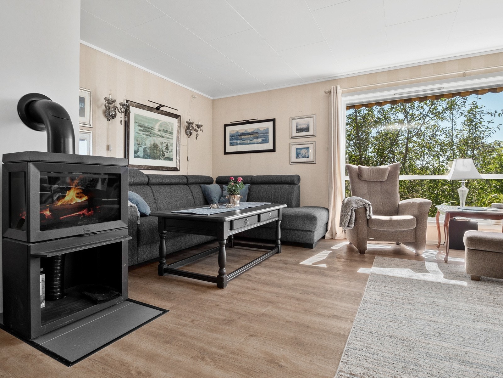 Det er store vinduer som sørger for lys, og fin peisovn med glassfelter som sørger for varme på kaldere dager Galleribilde