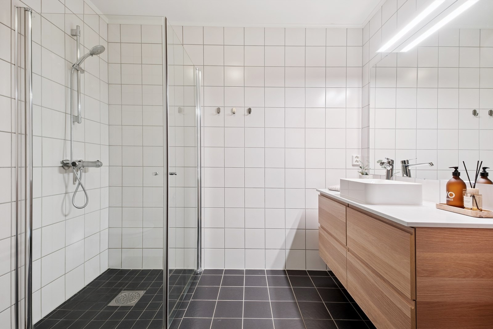 Badet er på 5,5 kvm og har et tidløst uttrykk. Ny innredning med vask og ekstra oppbevaringshylle er installert i 2023. Galleribilde