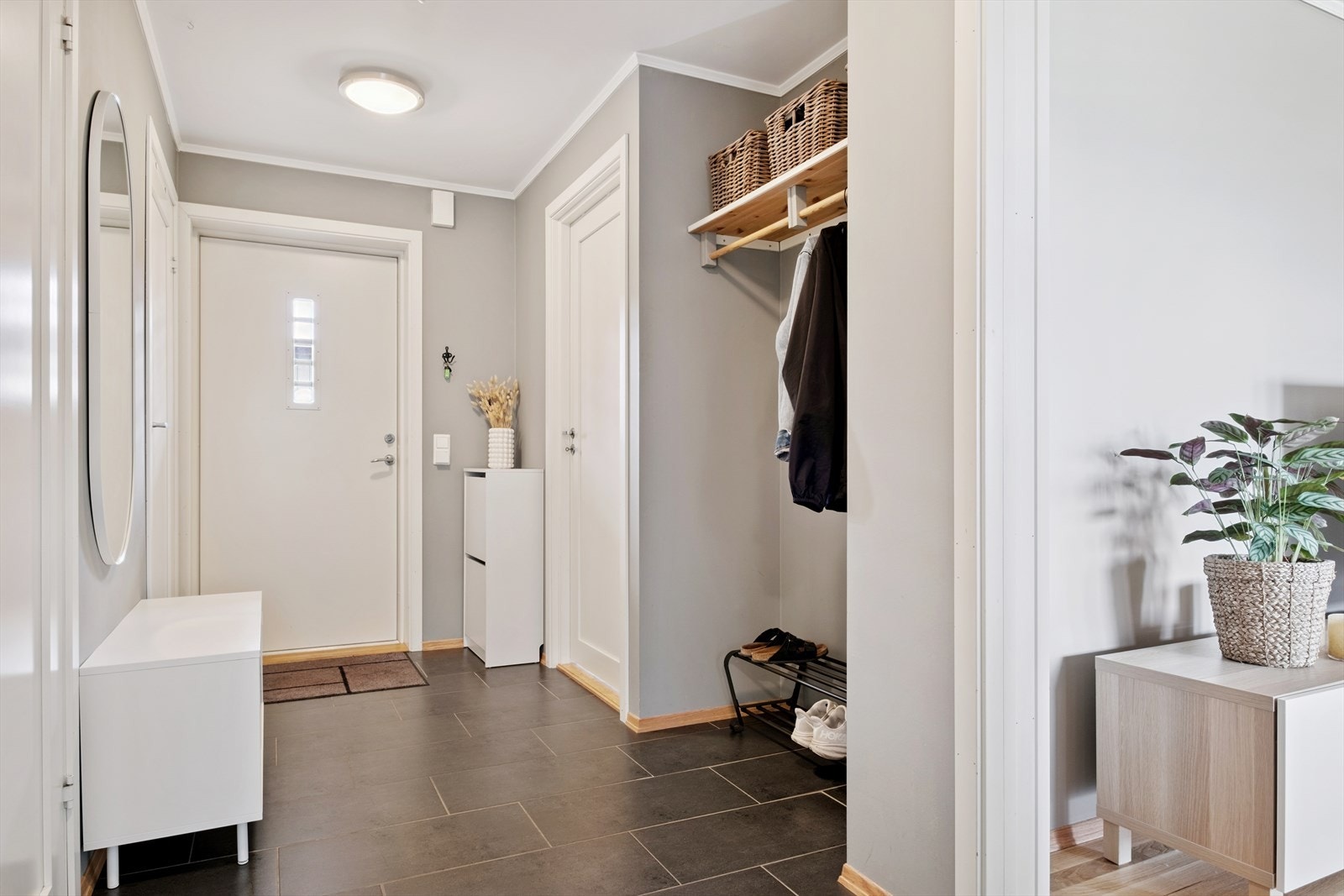 Man ønskes velkommen inn i en flislagt inngangsparti med god plass til å henge fra seg yttertøy. Galleribilde