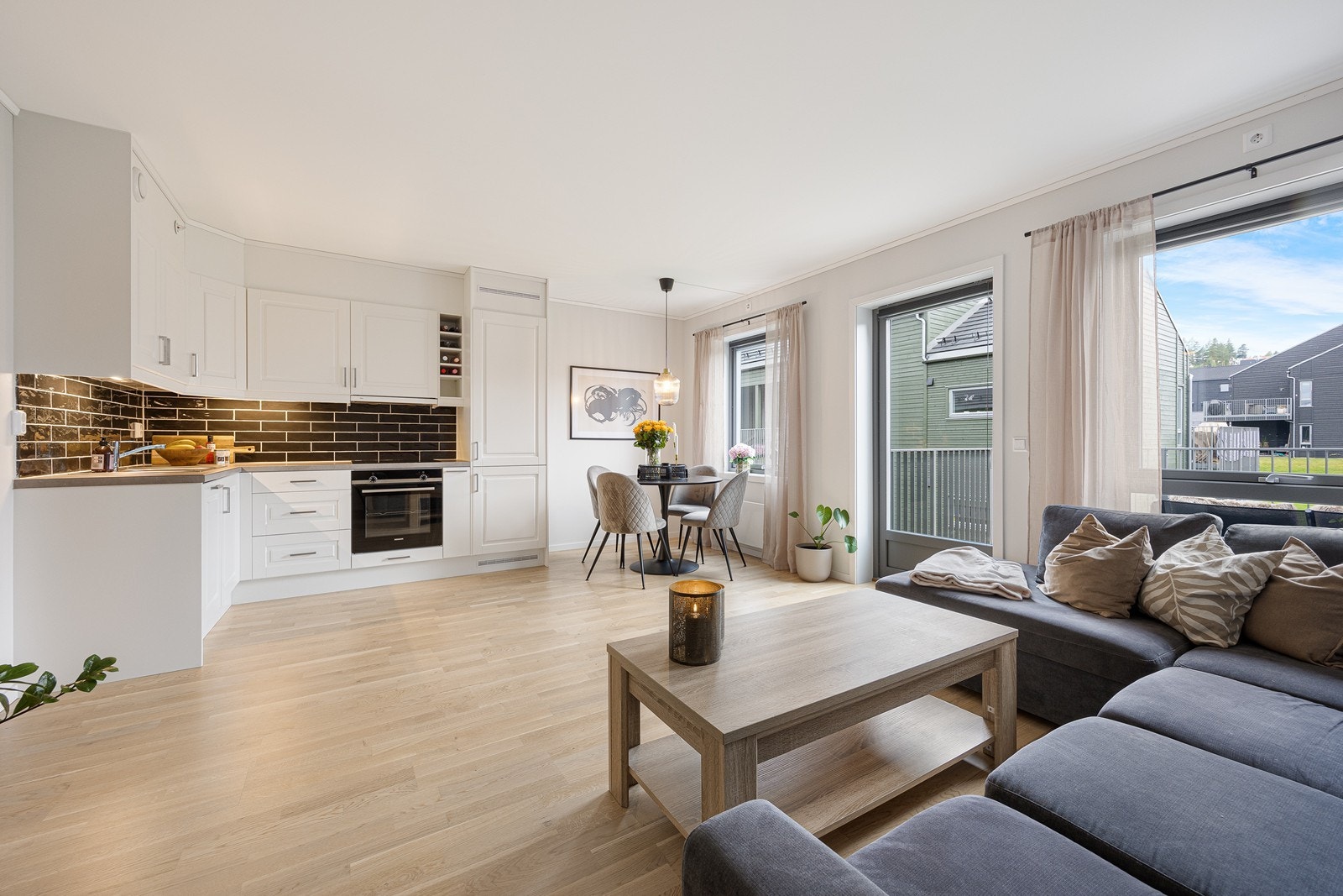 Innredningen har hvite, profilerte fronter, takoppforede skap og grå laminatbenkeplate med planlimt kum i stål. Galleribilde