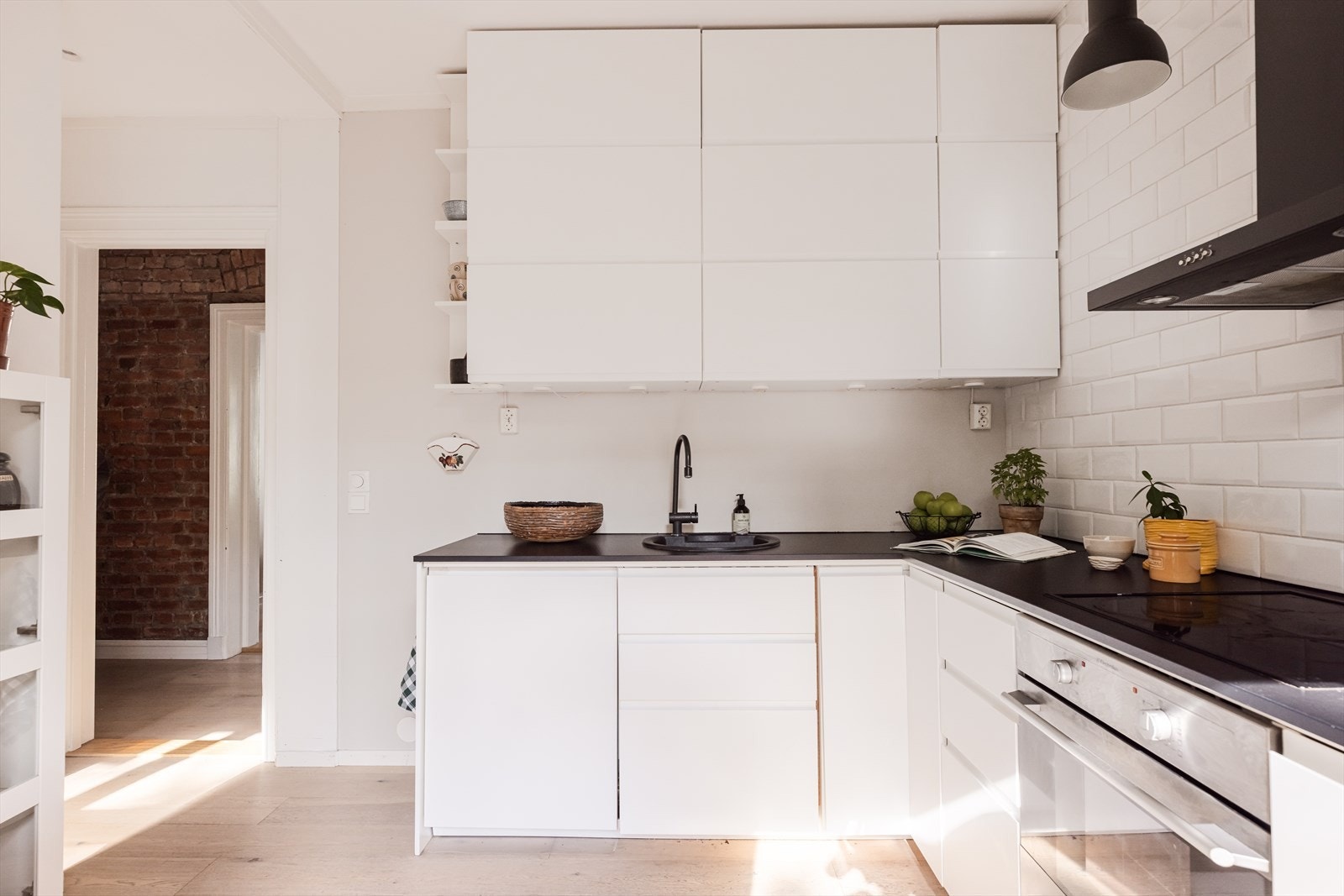 Kjøkkeninnredning med hvite glatte fronter, laminat benkeplate, oppvaskkum i kompositt og fliser over benk. Galleribilde