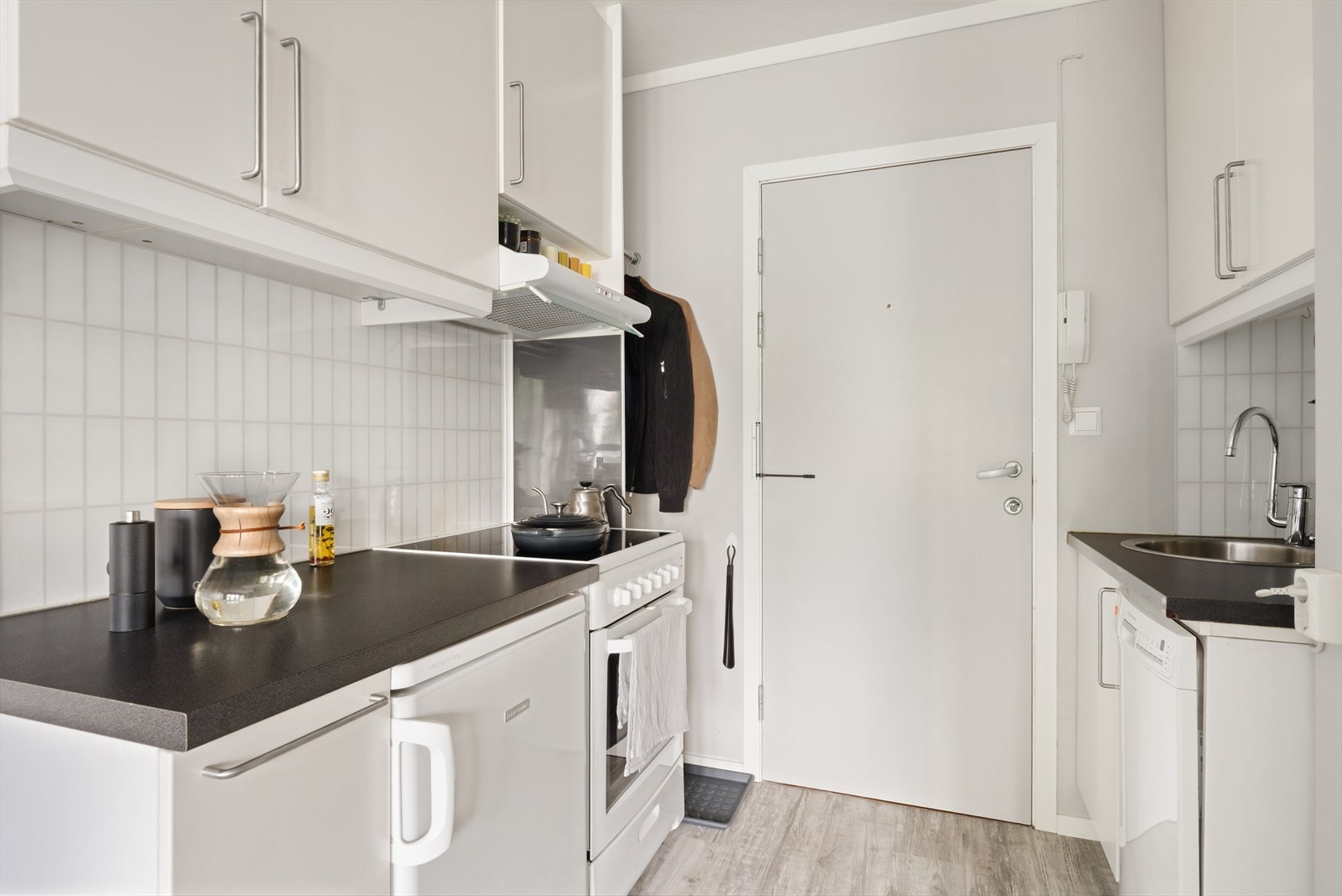 Kjøkkenet er praktisk innredet med glatte hvite fronter og benkeplate i laminat. Det er innredet med stekeovn, kjøleskap, oppvaskmaskin og lagringsplass. Galleribilde