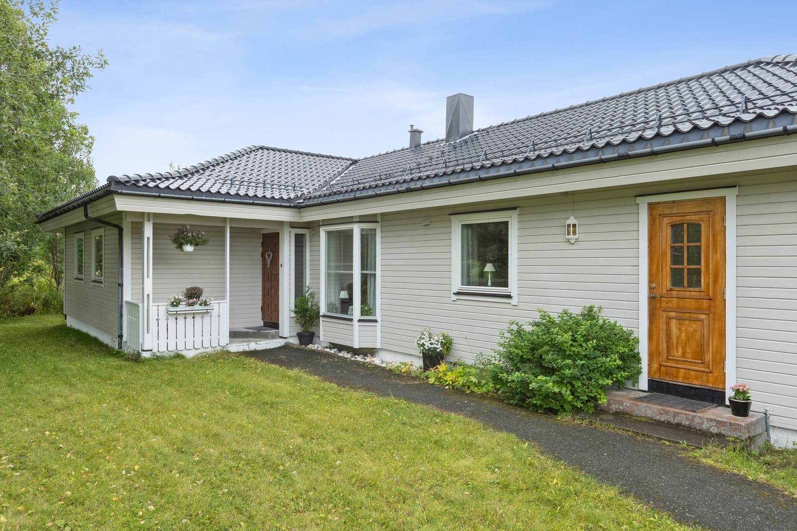 Pent opparbeidet hage med gressplen, beplantning og asfaltert gårdsplass Galleribilde