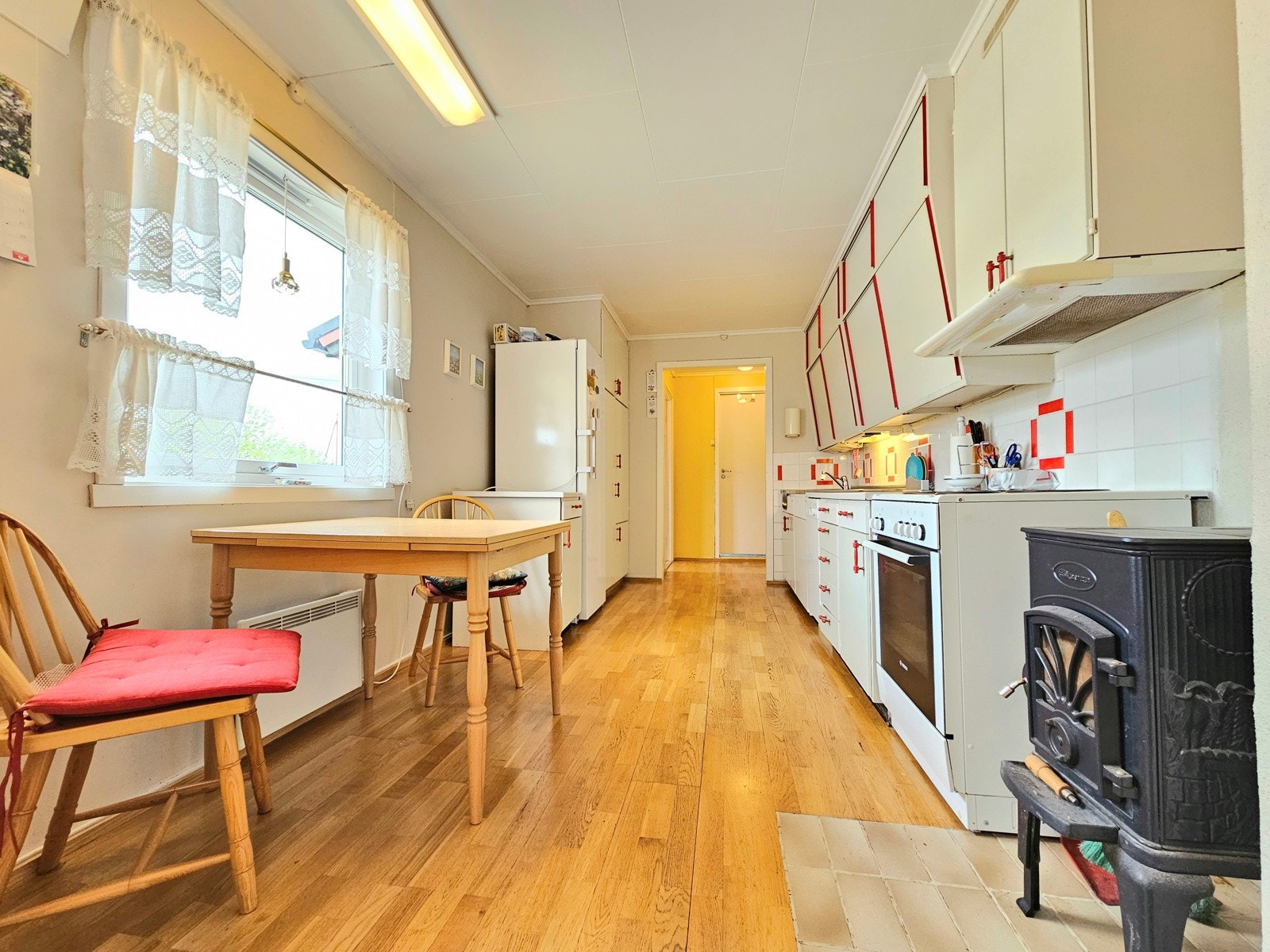 Det er installert vedovn på kjøkkenet og det er plass til et spisebord ved vinduet Galleribilde