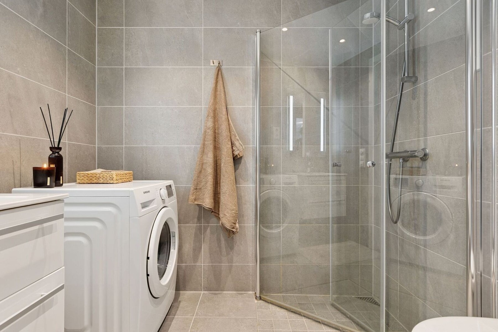 Flislagt baderom med opplegg for vaskemaskin, innfellbare dusjdører og behagelig gulvvarme. Galleribilde