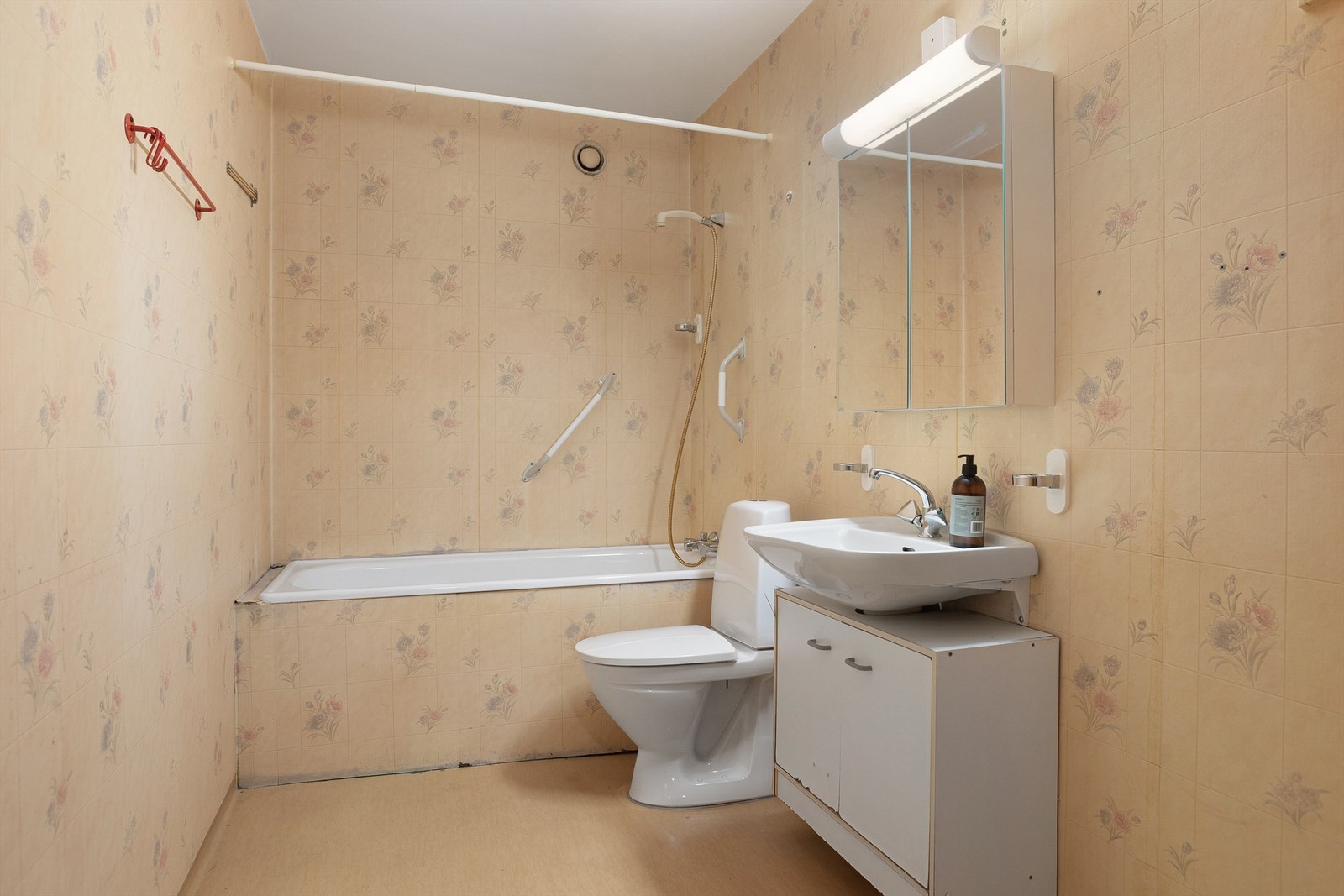 Bad med servant med overskap med speil og belysning, gulvstående toalett og badekar - renovering må påregnes Galleribilde