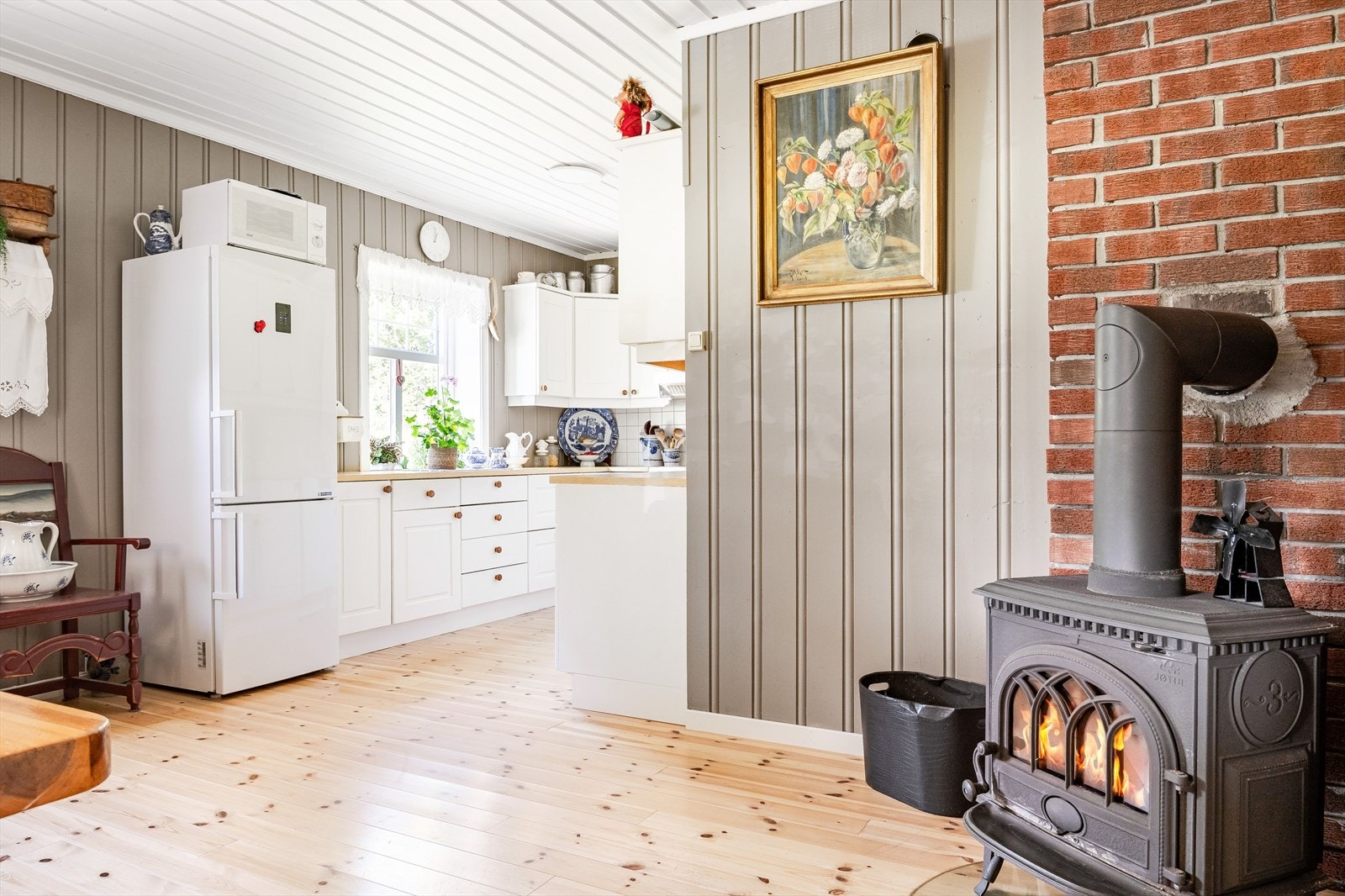 Kjøkkenet har lyse heltre furugulv og panel på veggene malt i en innbydende farge som gir en lun og god atmosfære. Galleribilde