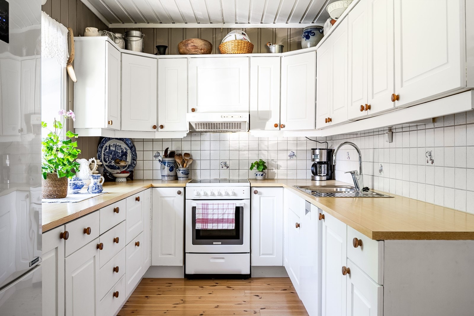 Innredningen har hvite profilerte fronter, laminert benkeplate med nedfelt oppvaskkum og fliser i benkeryggen. Galleribilde