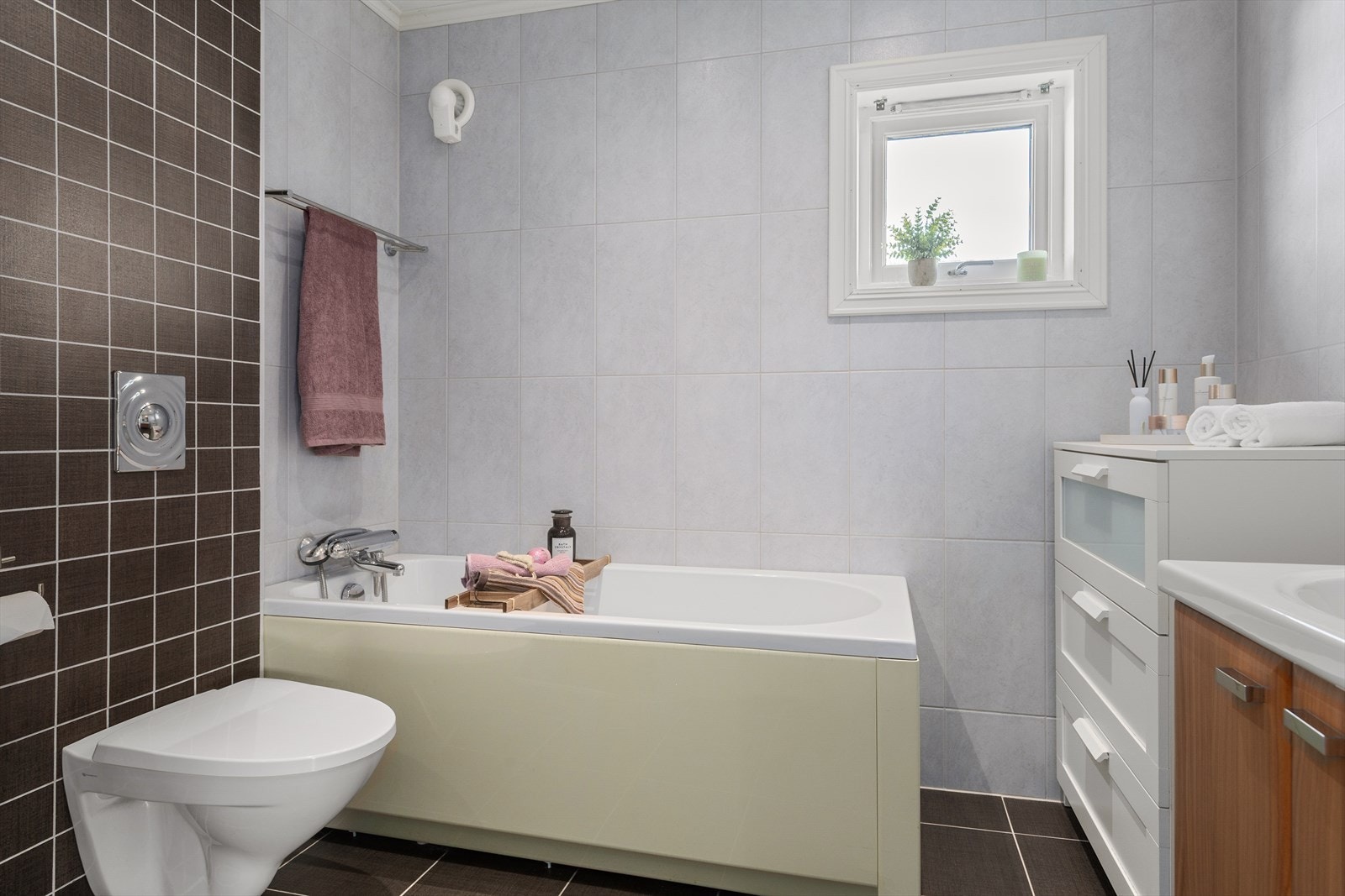 Badet på hovedplan er flislagt og innredet med toalett, badekar, dusjhjørne og servant. Galleribilde