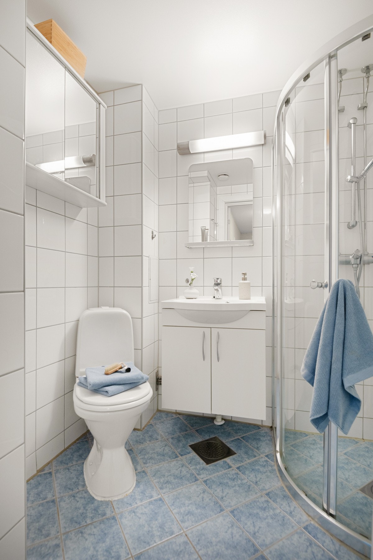 Rommet byr på toalett, servant med underskap. speil med belysning, veggskap og et lukket dusjhjørne med skyvedør. Galleribilde