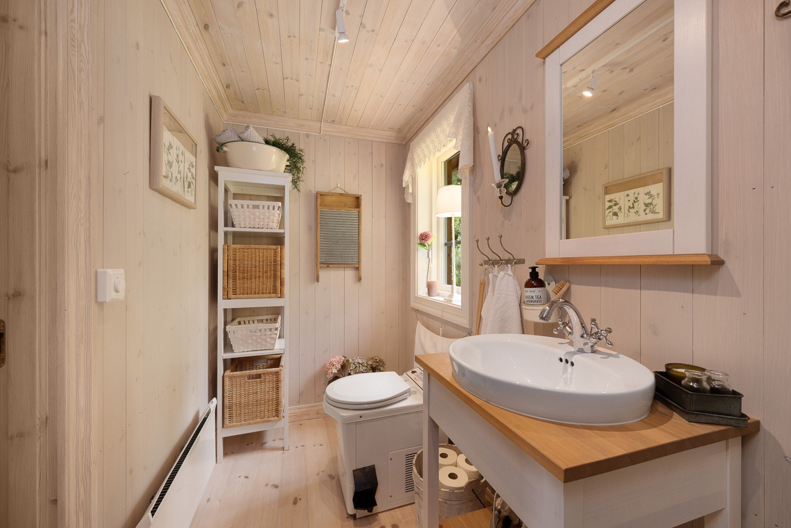 Santitærrommet er utstyrt med møbel med servant, speil, dusjkabinett, forbrenningstoalett og panelovn. Galleribilde