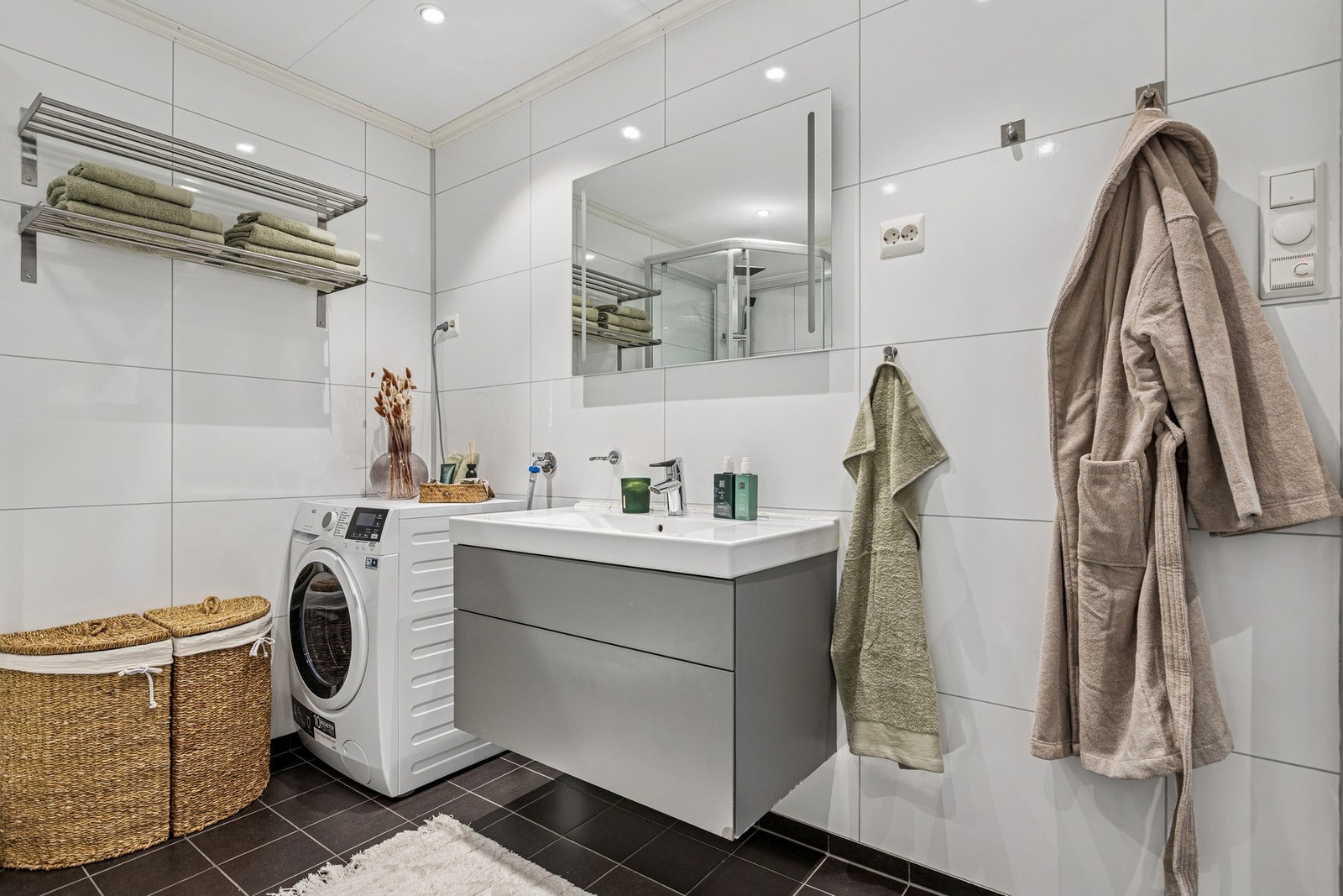 Baderommet er utstyrt med flislagt gulv med varme, dusjkabinnet, vegghengt toalett og opplegg for vaskemaskin. Galleribilde