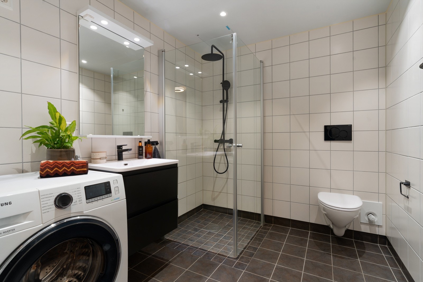 Badet fremstår stilig med gjennomgående sorte detaljer som bl.a. baderomsinnredningen og dusjbatteri fra Celeste med rainshower.