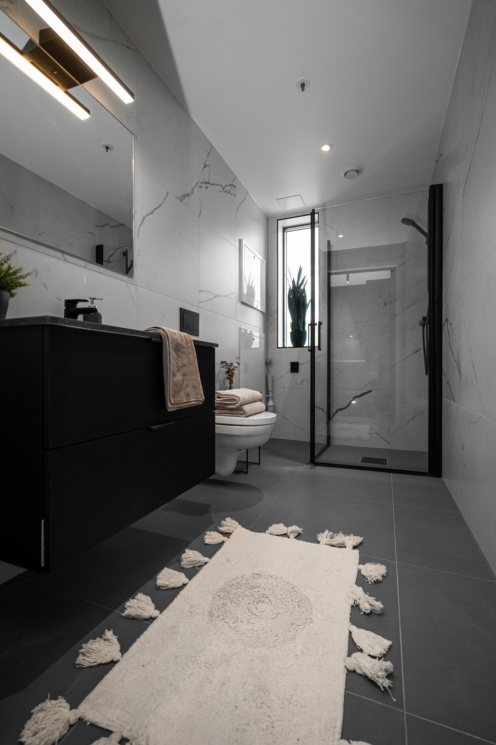 Badet er plassbygget og har porcelenato fliser med marmor struktur på vegger. Grå fliser på gulv. Strai innredning Galleribilde